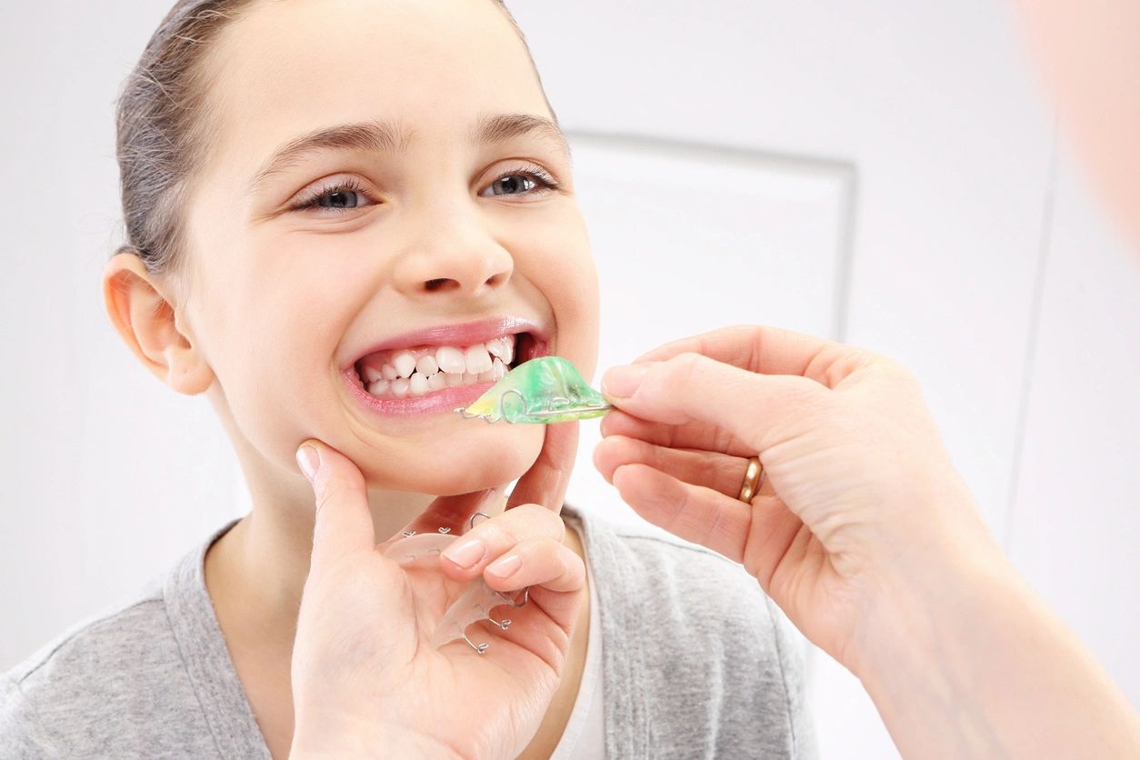 A girl is brushing her teeth with an adult.